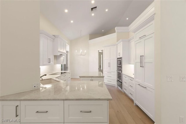 8723 La Palma Ln, Naples, FL 34108 - kitchen with a chandelier, vaulted ceiling, a center island, white cabinets, and light wood finished floors