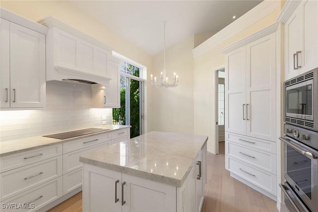 8723 La Palma Ln, Naples, FL 34108 - kitchen with stainless steel appliances, a chandelier, decorative backsplash, white cabinetry, and a kitchen island