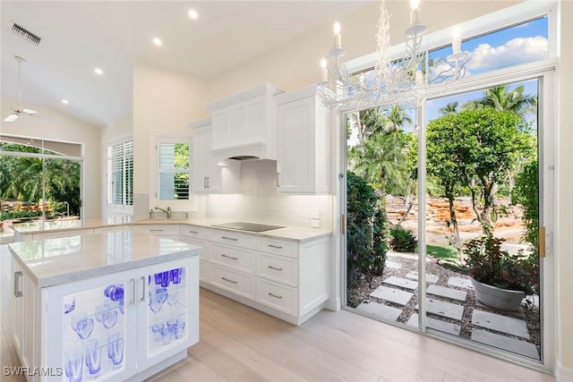 8723 La Palma Ln, Naples, FL 34108 - kitchen with black electric cooktop, backsplash, recessed lighting, light wood-type flooring, and white cabinetry