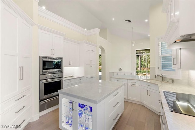 8723 La Palma Ln, Naples, FL 34108 - kitchen with stainless steel appliances, a warming drawer, arched walkways, white cabinets, and recessed lighting