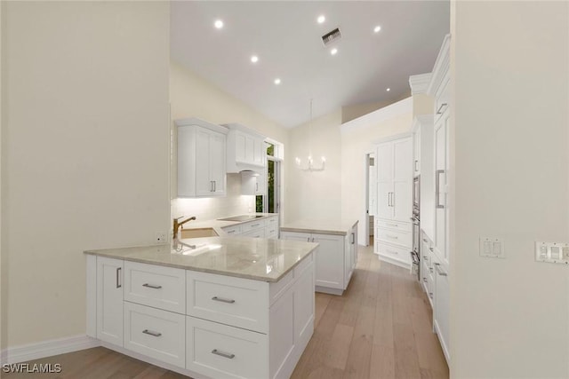 8723 La Palma Ln, Naples, FL 34108 - kitchen with a kitchen island, white cabinetry, light wood-type flooring, recessed lighting, and high vaulted ceiling