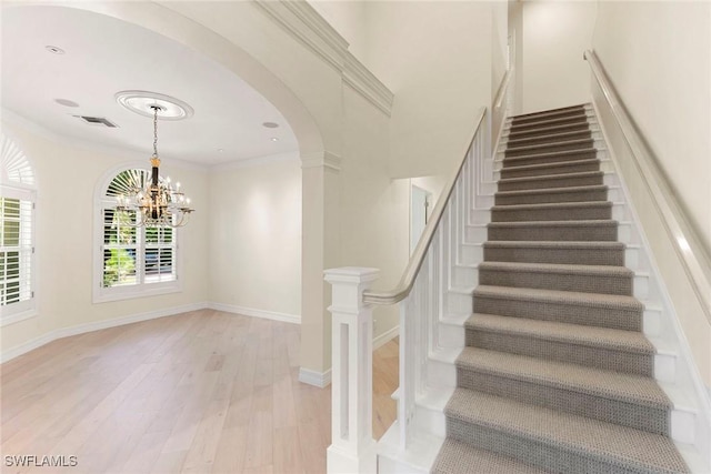 8723 La Palma Ln, Naples, FL 34108 - staircase with a chandelier, wood finished floors, arched walkways, and ornamental molding