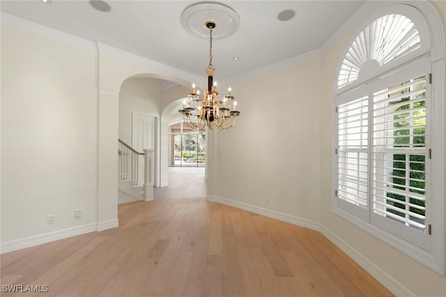 8723 La Palma Ln, Naples, FL 34108 - spare room featuring arched walkways, a chandelier, stairs, light wood-style flooring, and crown molding