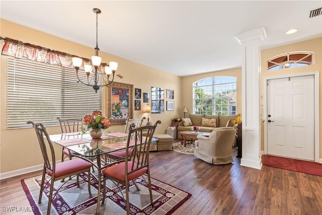 dining space featuring hardwood / wood-style floors, ornate columns, and an inviting chandelier