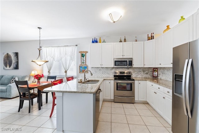 kitchen featuring sink, light stone countertops, appliances with stainless steel finishes, decorative light fixtures, and white cabinetry