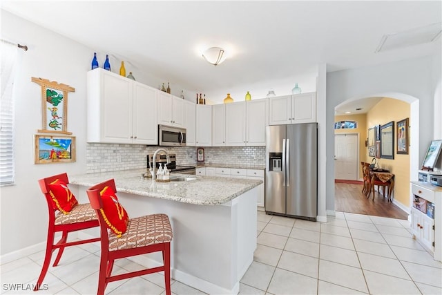 kitchen featuring kitchen peninsula, stainless steel appliances, a breakfast bar area, and light tile patterned flooring