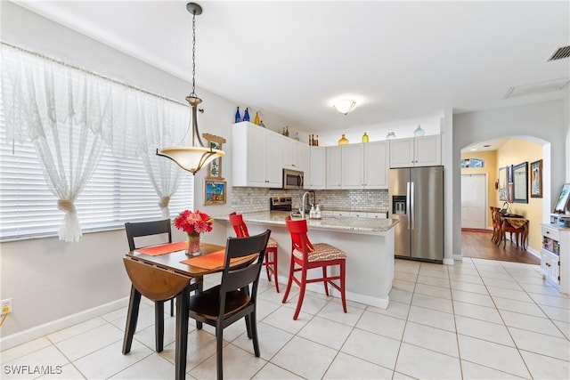 kitchen with white cabinets, light stone countertops, tasteful backsplash, decorative light fixtures, and stainless steel appliances