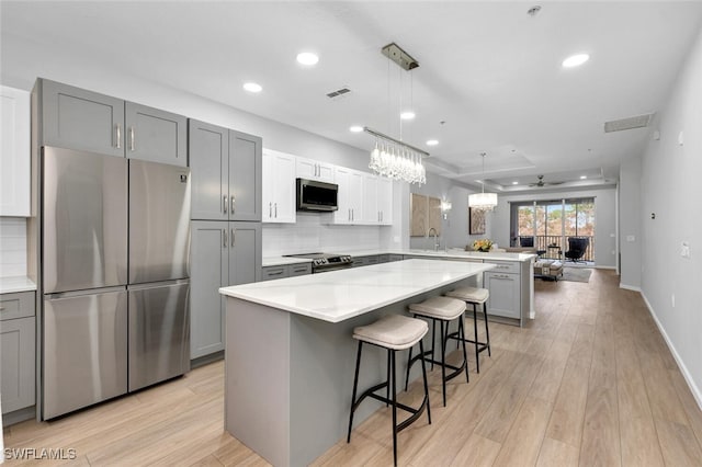 kitchen featuring kitchen peninsula, appliances with stainless steel finishes, a breakfast bar, ceiling fan, and pendant lighting