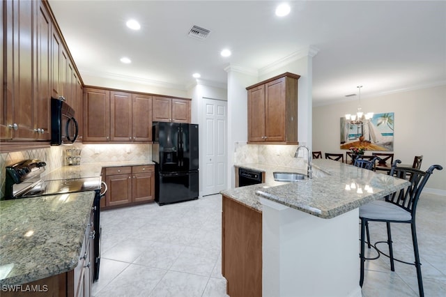 kitchen with black appliances, sink, light stone countertops, decorative light fixtures, and kitchen peninsula