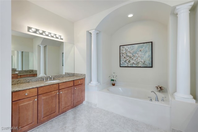 bathroom with a washtub, vanity, and tile patterned flooring