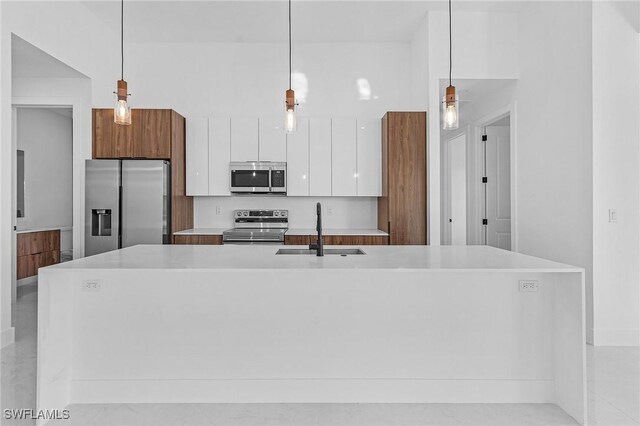 kitchen featuring a center island with sink, hanging light fixtures, sink, and appliances with stainless steel finishes