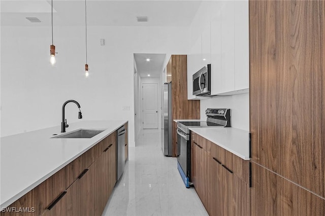 kitchen with pendant lighting, sink, white cabinetry, and stainless steel appliances