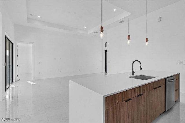 kitchen featuring stainless steel dishwasher, sink, a kitchen island with sink, and a tray ceiling