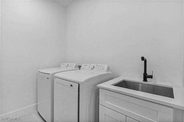 clothes washing area featuring separate washer and dryer, sink, and cabinets