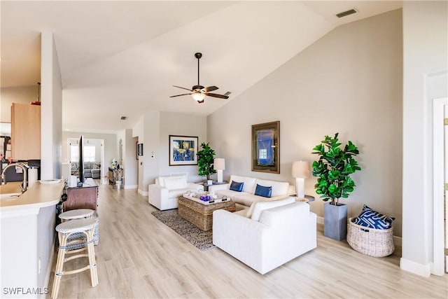 living room with ceiling fan, light hardwood / wood-style flooring, lofted ceiling, and sink