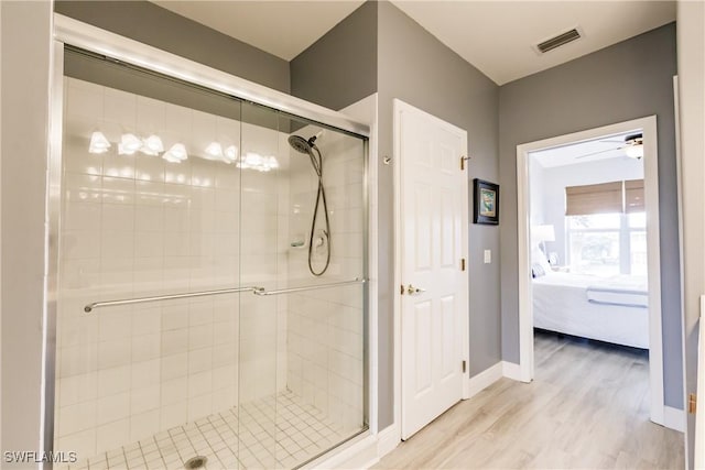 bathroom featuring ceiling fan, wood-type flooring, and a shower with door