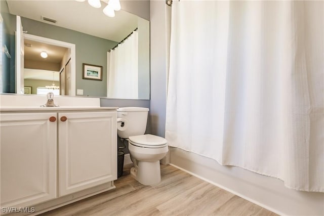 full bathroom featuring hardwood / wood-style flooring, shower / bath combo, toilet, and vanity