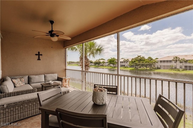 sunroom with ceiling fan and a water view