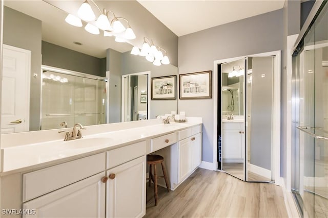 bathroom with hardwood / wood-style flooring, vanity, and a shower with door