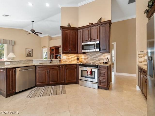 kitchen featuring decorative backsplash, appliances with stainless steel finishes, light stone countertops, sink, and lofted ceiling