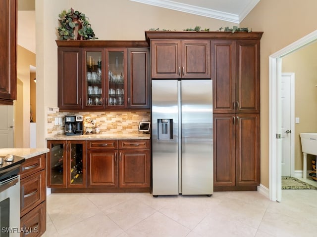 kitchen featuring stainless steel refrigerator with ice dispenser, vaulted ceiling, decorative backsplash, light stone countertops, and ornamental molding