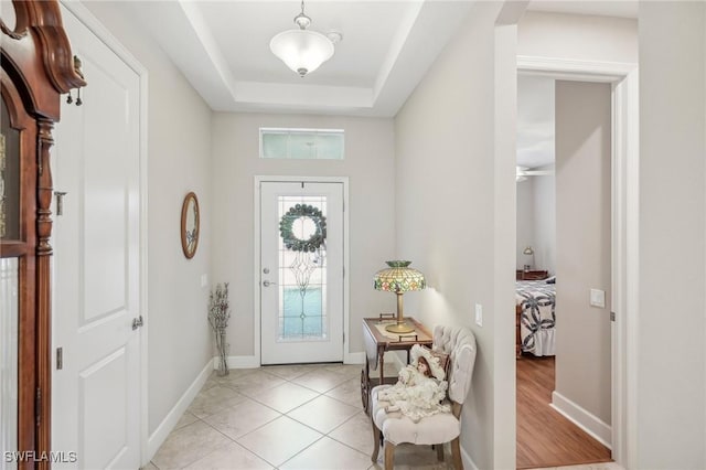 foyer entrance featuring light tile patterned floors and a tray ceiling