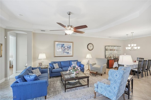 tiled living room with ornamental molding, a raised ceiling, and ceiling fan with notable chandelier