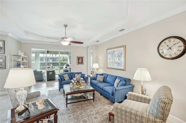 tiled living room with ornamental molding, ceiling fan, and a tray ceiling