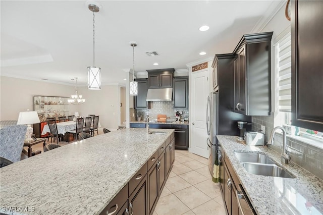 kitchen with sink, tasteful backsplash, pendant lighting, and light stone counters