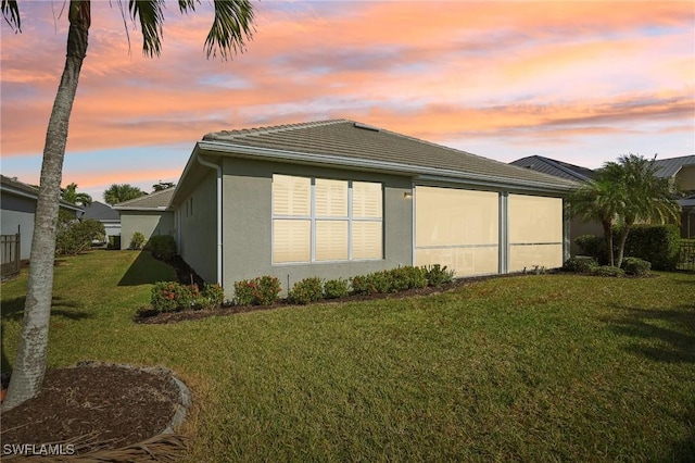 property exterior at dusk featuring a yard