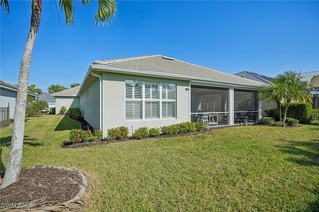 back of house featuring a lawn and a sunroom