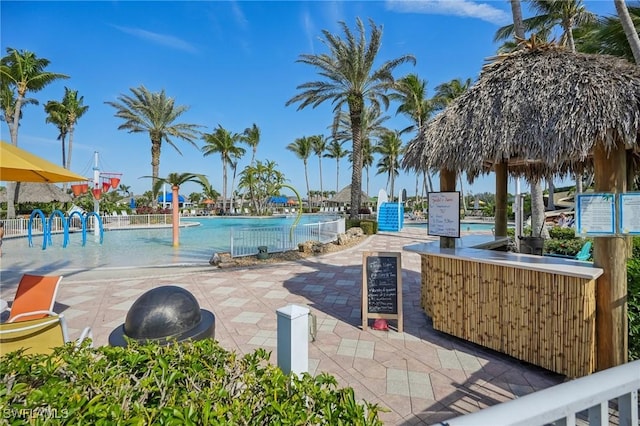 pool featuring a patio area, fence, and a water play area