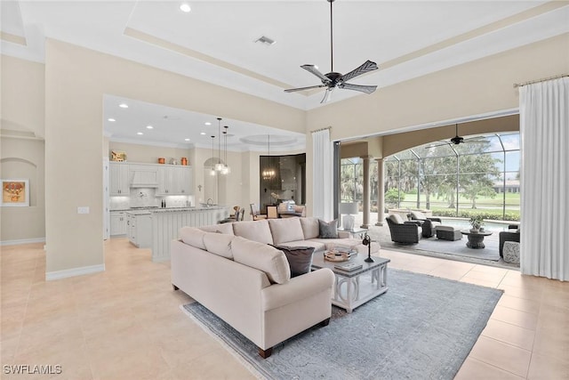 living room featuring ceiling fan, a tray ceiling, and light tile patterned floors