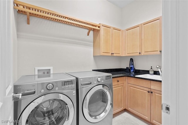 clothes washing area with light tile patterned floors, sink, washing machine and dryer, and cabinets