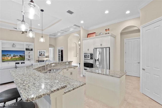 7440 Byrons Way, Naples, FL 34113 - kitchen with stainless steel appliances, a large island with sink, arched walkways, ornamental molding, and open floor plan