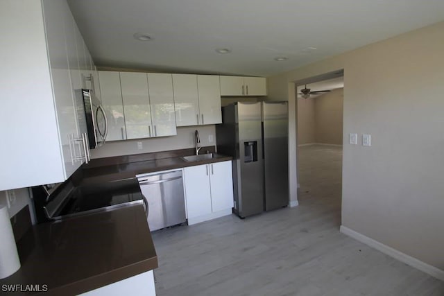 kitchen with appliances with stainless steel finishes, light wood-type flooring, ceiling fan, sink, and white cabinets