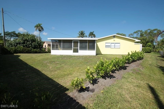 rear view of house featuring a yard and a sunroom