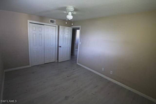 unfurnished bedroom with hardwood / wood-style floors, a closet, and ceiling fan