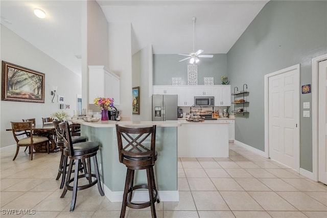 kitchen featuring white cabinetry, stainless steel appliances, high vaulted ceiling, kitchen peninsula, and a breakfast bar