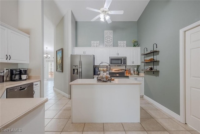 kitchen with white cabinets, ceiling fan with notable chandelier, light tile patterned floors, appliances with stainless steel finishes, and a kitchen island