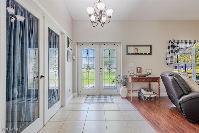 entryway with tile patterned flooring, french doors, a healthy amount of sunlight, and a notable chandelier