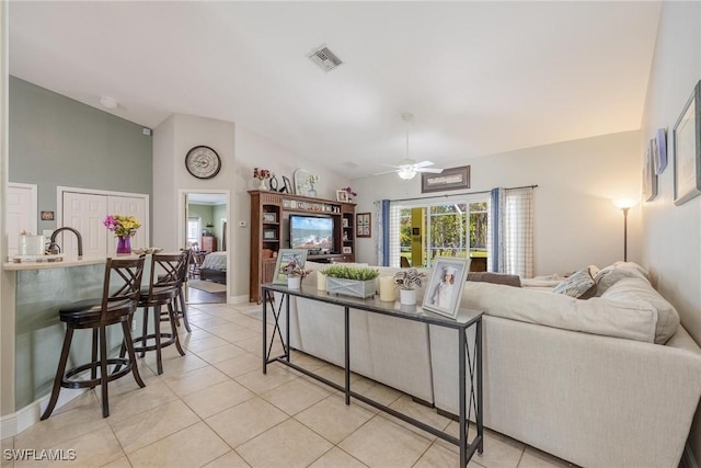 tiled living room featuring ceiling fan, sink, and vaulted ceiling