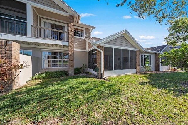 rear view of house with a yard and a sunroom