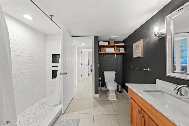 bathroom with tile patterned flooring, vanity, tiled shower, and toilet