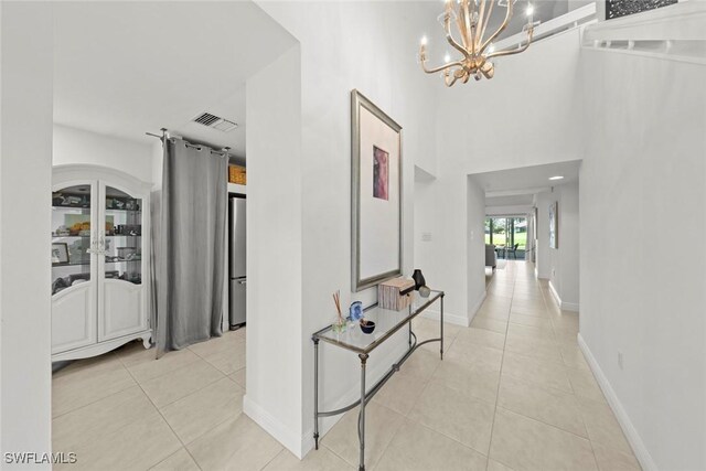 hall with a notable chandelier and light tile patterned flooring