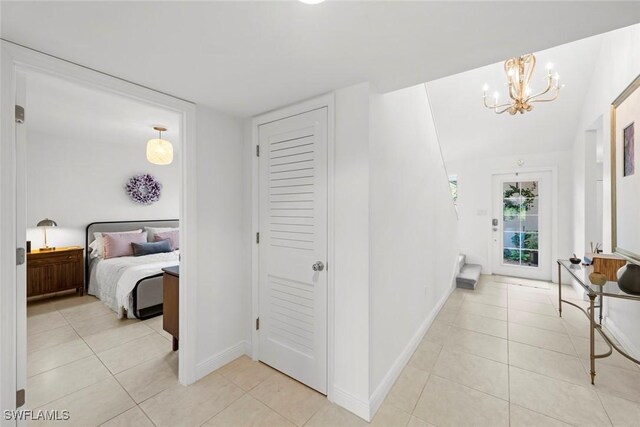 hall with light tile patterned floors and an inviting chandelier