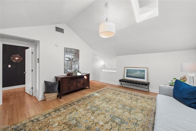 interior space featuring vaulted ceiling, wood finished floors, visible vents, and baseboards