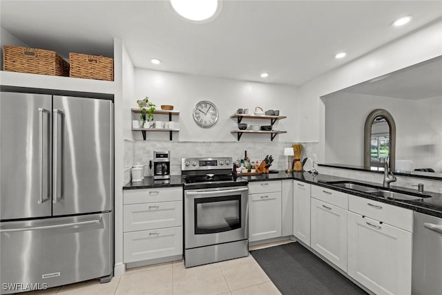 kitchen with sink, stainless steel appliances, white cabinets, light tile patterned flooring, and dark stone counters