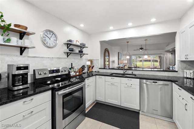 kitchen featuring light tile patterned floors, dark stone counters, appliances with stainless steel finishes, open shelves, and a sink