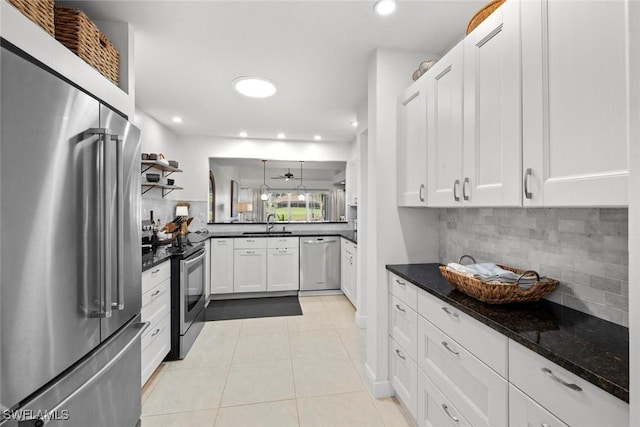 kitchen featuring light tile patterned floors, decorative backsplash, white cabinets, appliances with stainless steel finishes, and dark stone countertops